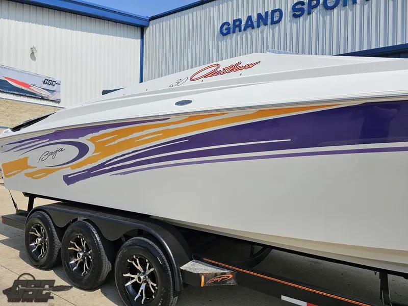 Slide: The Image of 2004 Baja 30 Outlaw boat with vibrant graphics on a trailer at Grand Sport Center. - 13