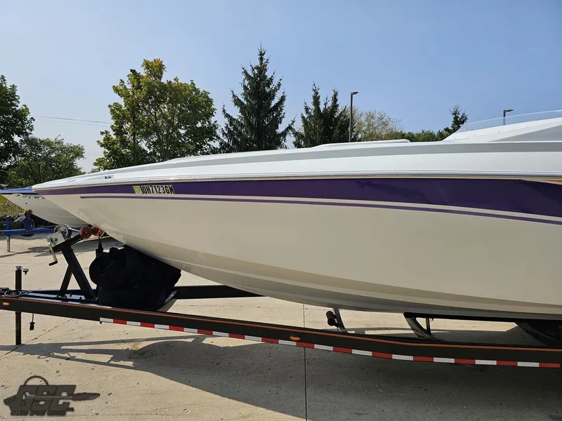 Slide: The Image of 2004 Baja 30 Outlaw speedboat on trailer, white with purple stripe, parked outdoors. - 22