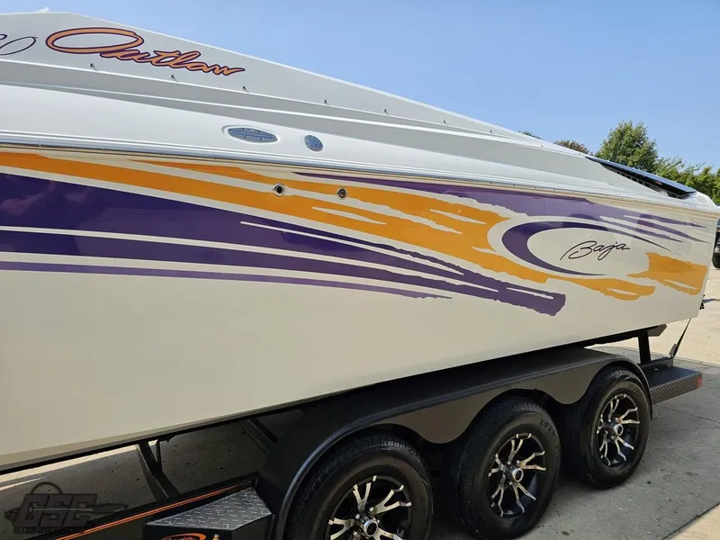 Slide: The Image of 2004 Baja 30 Outlaw boat with vibrant purple and orange graphics on a trailer. - 24