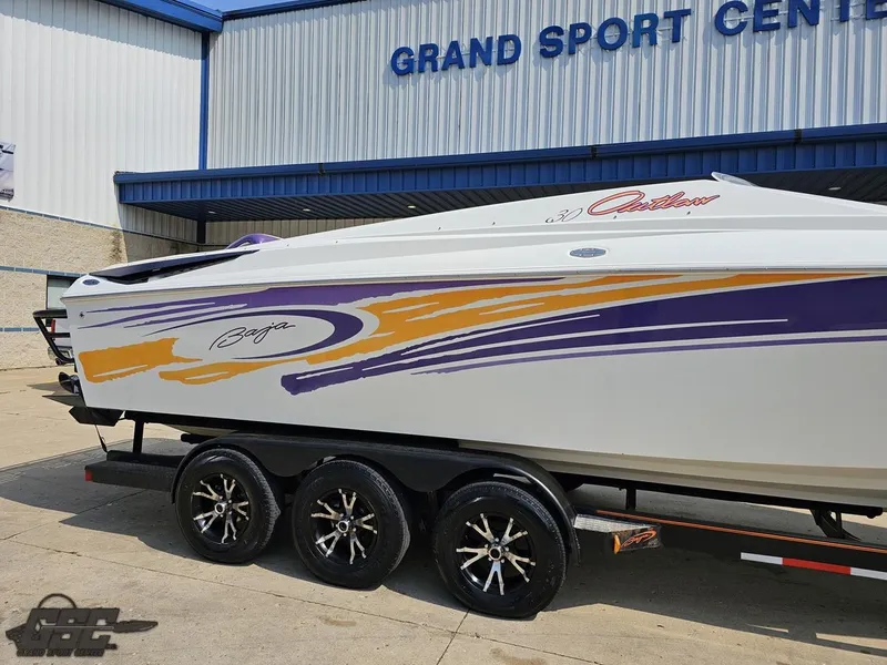 Slide: The Image of 2004 Baja 30 Outlaw boat with vibrant graphics on a trailer at Grand Sport Center. - 5