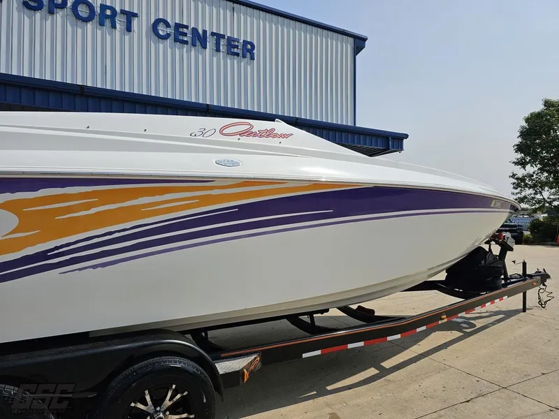 Slide: The Image of 2004 Baja 30 Outlaw boat with vibrant graphics on a trailer outside a sport center. - 8