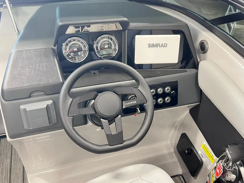 Slide: The Image of 2025 Harris Solstice DC 250 boat dashboard with steering wheel and Simrad display. - 12