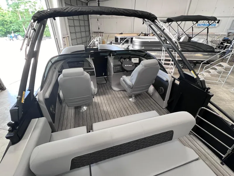 Slide: The Image of 2025 Harris Solstice DC 250 boat interior with modern seating and controls in a showroom. - 19