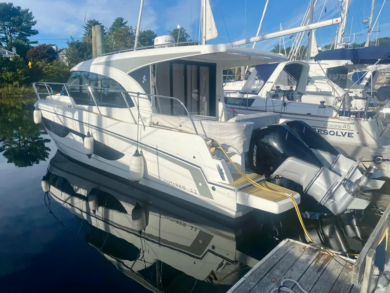 Slide: The Image of 2022 Beneteau Antares 11 docked at marina, reflecting on calm water. - 2