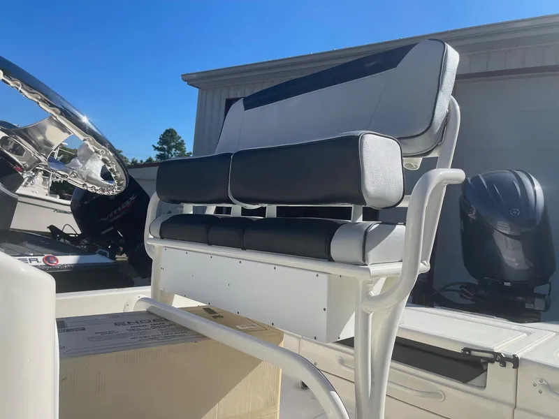 Slide: The Image of 2025 Skeeter SX221 boat seat with black and white upholstery, steering wheel, and motor in background. - 2