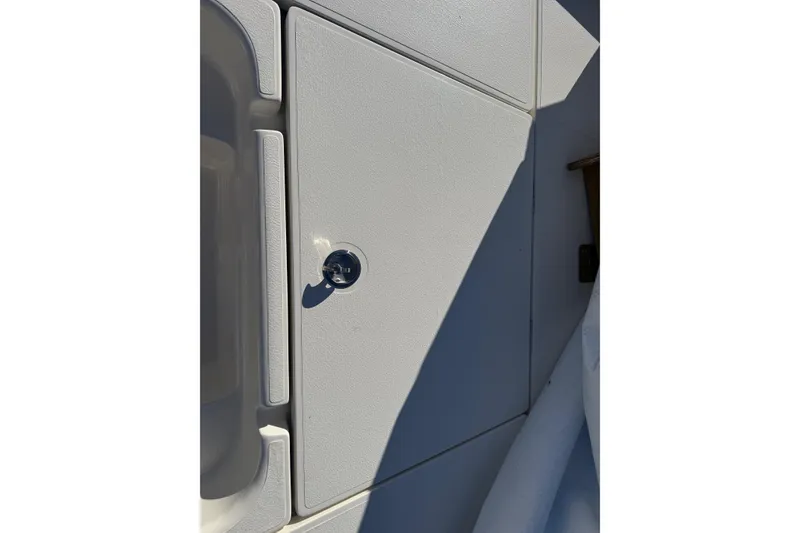Slide: The Image of 2025 Skeeter SX221 boat compartment with key lock, white surface, and shadow detail. - 25