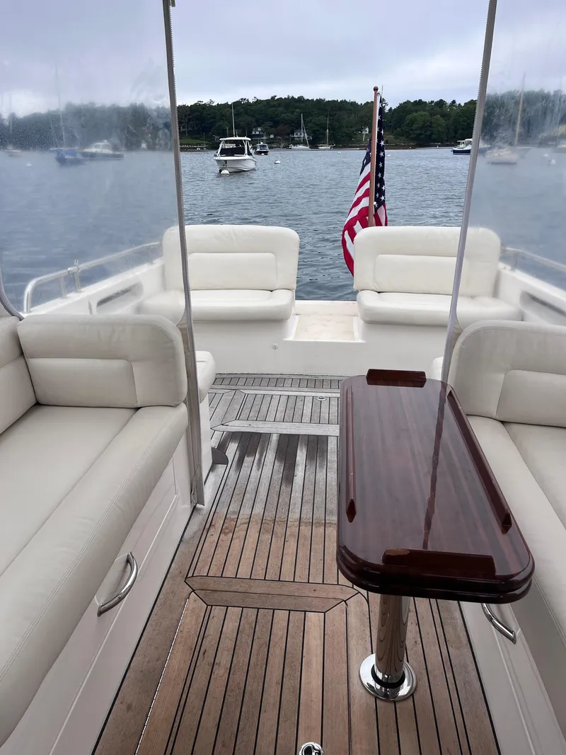 Slide: The Image of 2014 MJM 36z Downeast boat interior with seating and wooden table, docked on a calm lake. - 37