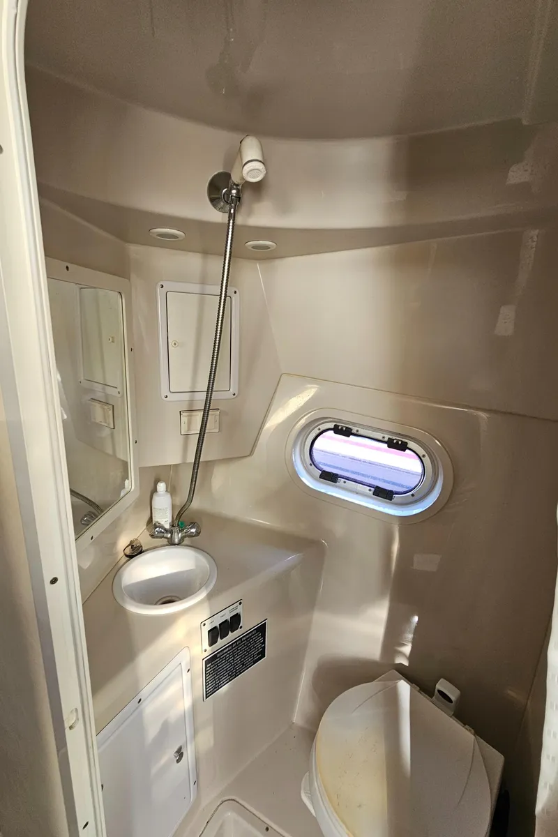 Slide: The Image of 2002 Four Winns 248 Vista boat bathroom with sink, shower, and porthole window. - 15