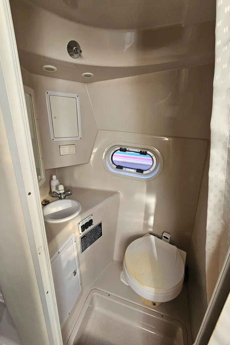 Slide: The Image of 2002 Four Winns 248 Vista boat bathroom with sink, toilet, and porthole window. - 16