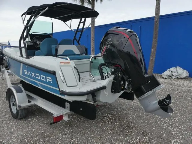 Slide: The Image of 2022 Saxdor SX 200 boat on trailer with outboard motor, parked outdoors. - 12