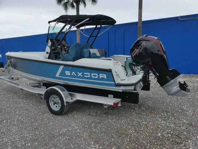Slide: The Image of 2022 Saxdor SX 200 boat on trailer with outboard motor, parked outdoors. - 13