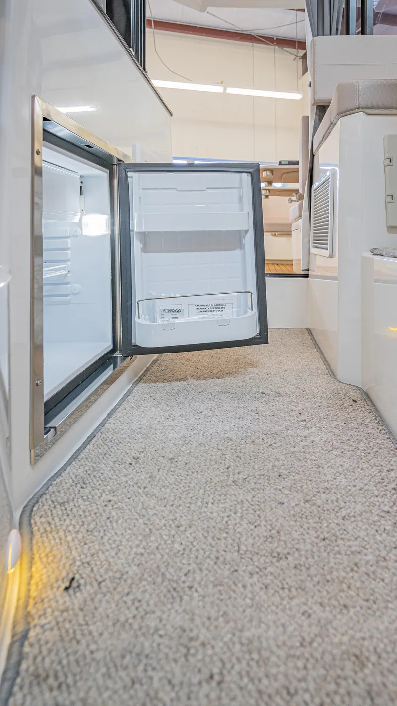 Slide: The Image of 2024 Skamander 920 Explorer MAX interior with open mini fridge on carpeted floor. - 13