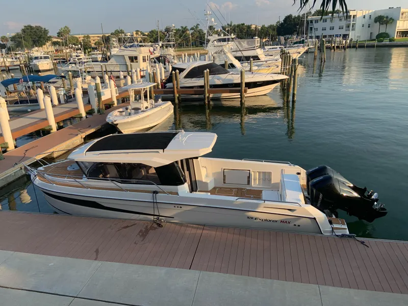 Slide: The Image of 2024 Skamander 920 Explorer MAX docked at a marina with other boats. - 2