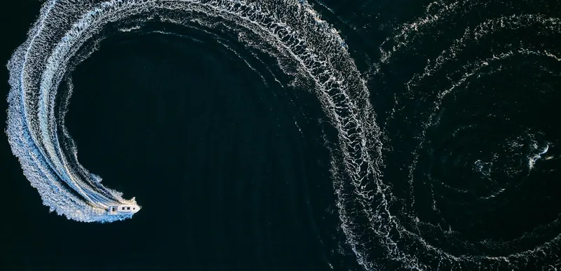 Slide: The Image of Aerial view of 2024 Skamander 920 Explorer MAX creating circular wake patterns on water. - 27