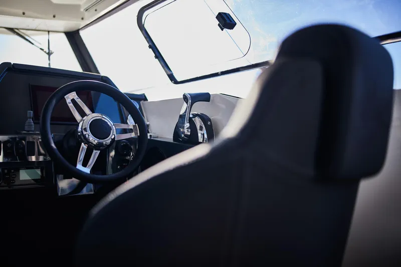 Slide: The Image of Interior of 2024 Skamander 920 Explorer MAX boat, featuring steering wheel and controls. - 32