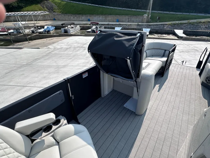 Slide: The Image of 2025 Starcraft RX 25 DL DC boat interior with seating and cup holders at a marina. - 10