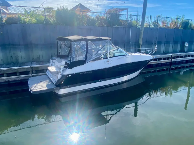 Slide: The Image of 2019 Four Winns Vista 275 boat docked in calm waters under a clear sky. - 0