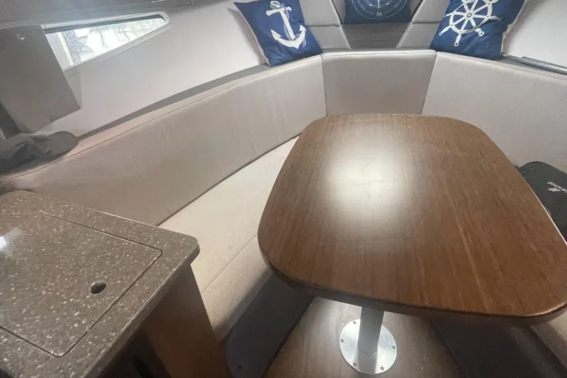 Slide: The Image of 2019 Four Winns Vista 275 interior with wooden table and nautical-themed cushions. - 31