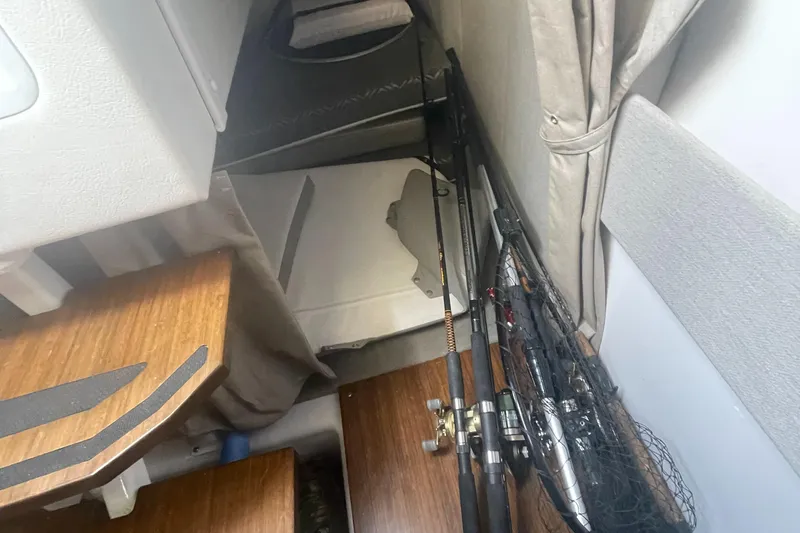 Slide: The Image of Interior of 2019 Four Winns Vista 275 with fishing rods and wooden surfaces. - 35