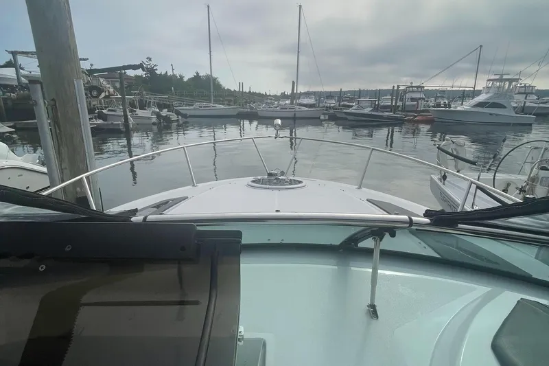 Slide: The Image of 2019 Four Winns Vista 275 boat docked in a marina, surrounded by other vessels. - 43