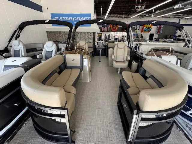 Slide: The Image of 2025 Starcraft EXS 1 pontoon boat interior with beige seating in showroom. - 3