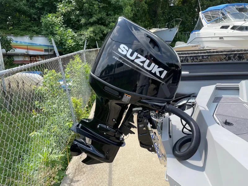 Slide: The Image of 2024 Thor 1860 Lake Hammer boat with Suzuki outboard motor, docked near greenery and other boats. - 11