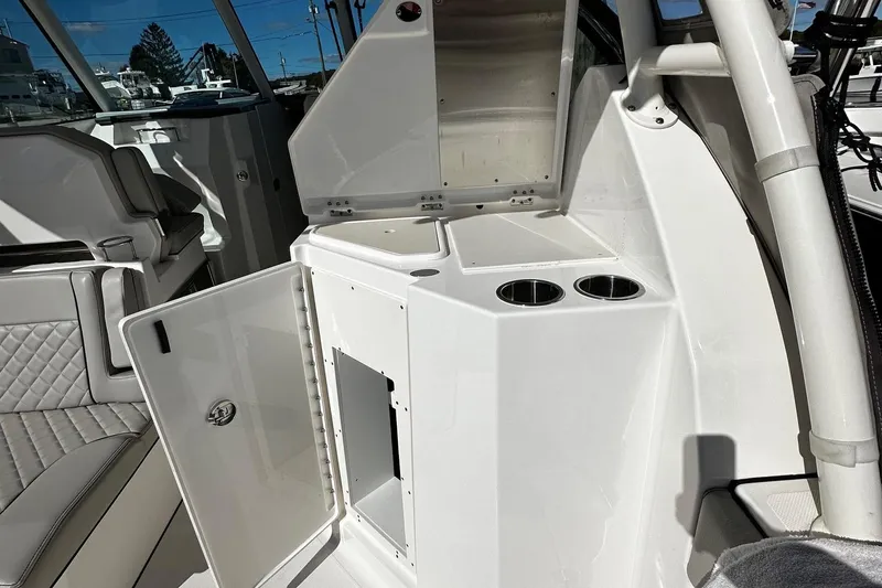 Slide: The Image of 2022 Pursuit DC 295 Dual Console interior with open storage and cup holders. - 12