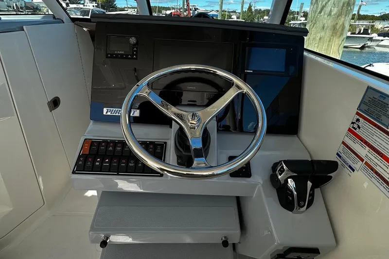 Slide: The Image of 2022 Pursuit DC 295 Dual Console boat helm with steering wheel and control panel. - 14