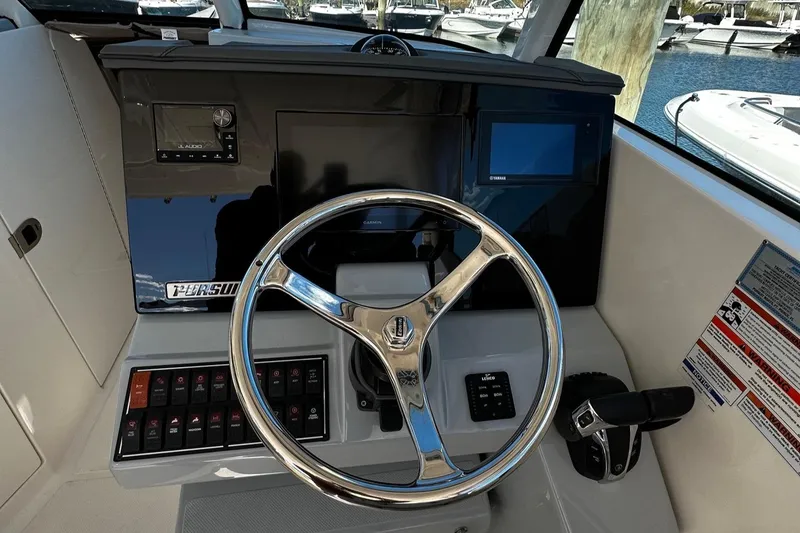 Slide: The Image of 2022 Pursuit DC 295 Dual Console boat helm with steering wheel and control panel. - 15