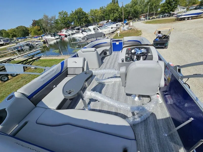 Slide: The Image of 2025 Bennington 22 SXSB pontoon boat at marina, featuring spacious seating and modern controls. - 12