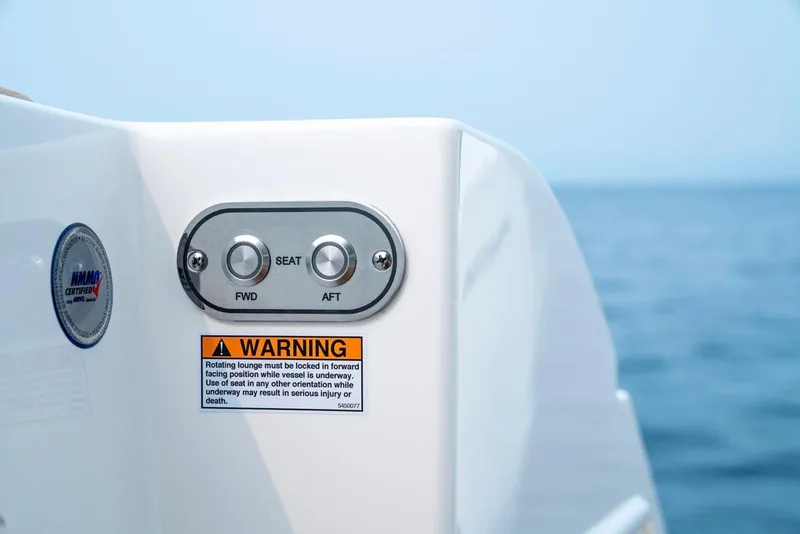 Slide: The Image of Tiara Yachts 48 LE 2025 seat controls with warning label, ocean background. - 31