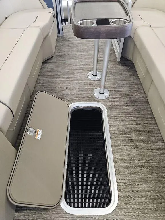Slide: The Image of 2025 Godfrey Sweetwater 2486 SFL boat interior with open storage compartment and table. - 10