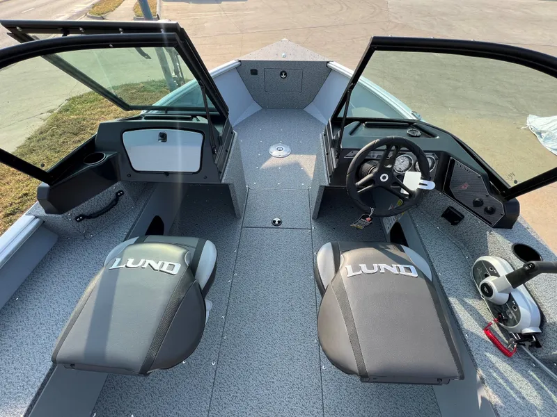 Slide: The Image of 2025 Lund 1875 Alaskan Sport boat interior with open windshield and dual seats. - 12