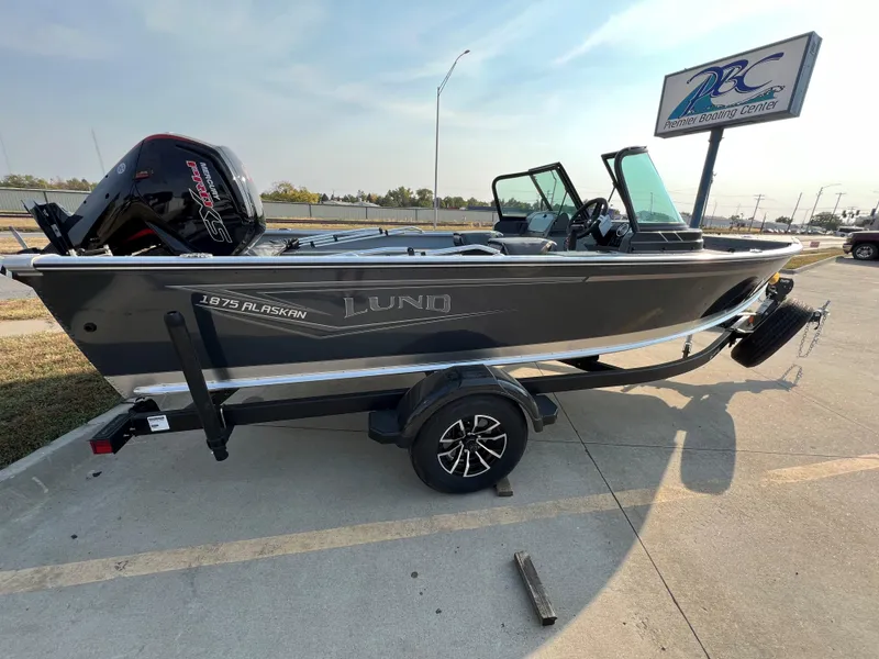 Slide: The Image of 2025 Lund 1875 Alaskan Sport boat on trailer in parking lot. - 2