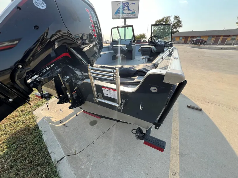 Slide: The Image of 2025 Lund 1875 Alaskan Sport boat with outboard motor and ladder, parked outdoors. - 3