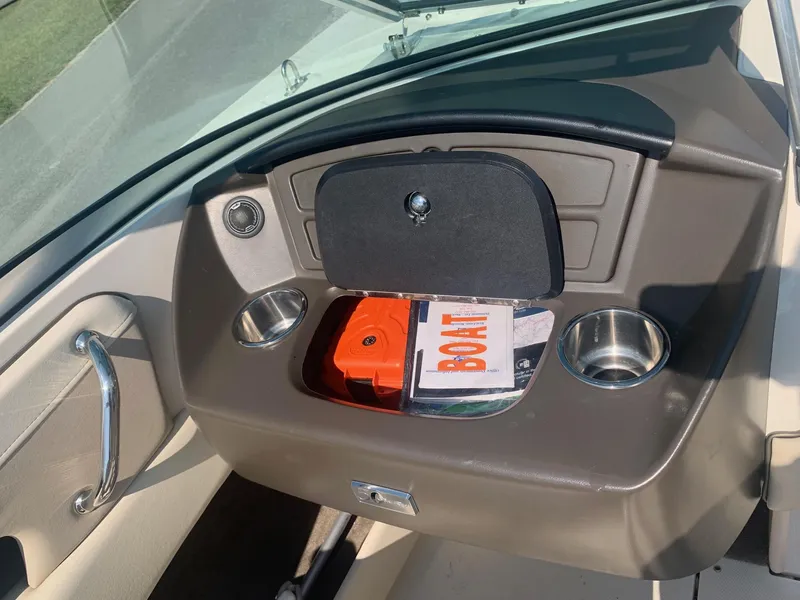 Slide: The Image of 2009 Sea Ray 230 Sundeck dashboard with storage compartment and cup holders. - 13