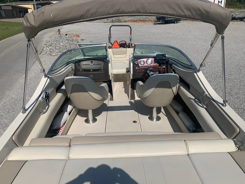 Slide: The Image of 2009 Sea Ray 230 Sundeck interior with seating and dashboard, featuring a bimini top. - 17