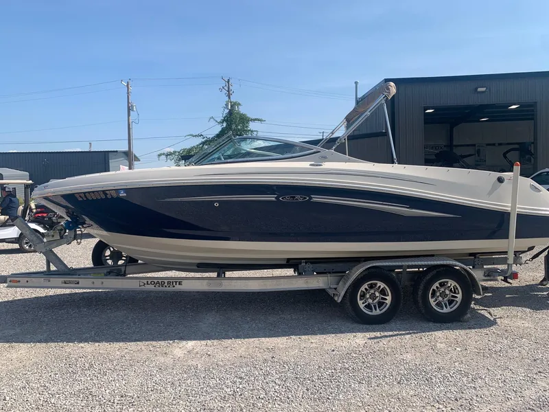 Slide: The Image of 2009 Sea Ray 230 Sundeck boat on trailer, parked outdoors. - 2