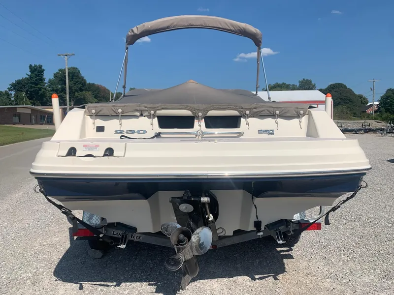 Slide: The Image of 2009 Sea Ray 230 Sundeck boat, rear view, parked on gravel under clear sky. - 5