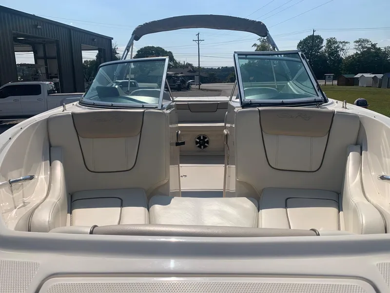 Slide: The Image of 2009 Sea Ray 230 Sundeck boat interior with seating and windshield, parked outdoors. - 7