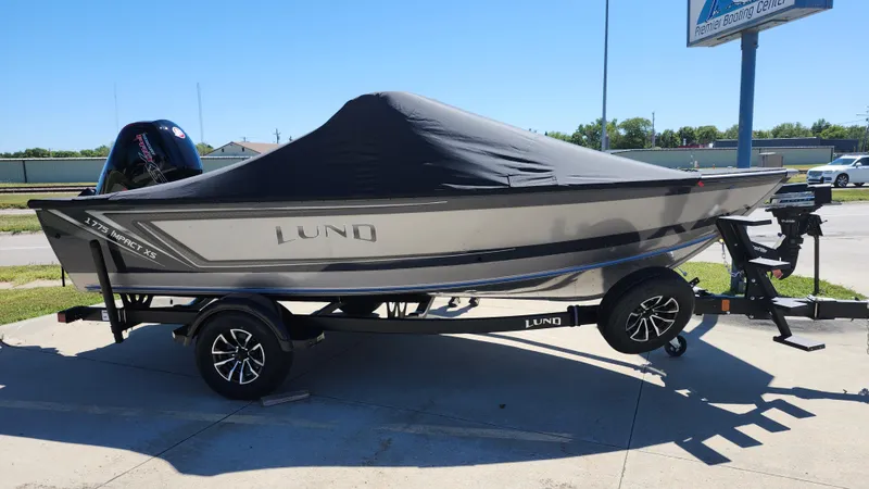 Slide: The Image of 2025 Lund 1775 Impact XS Sport boat with cover on trailer, parked outdoors. - 15