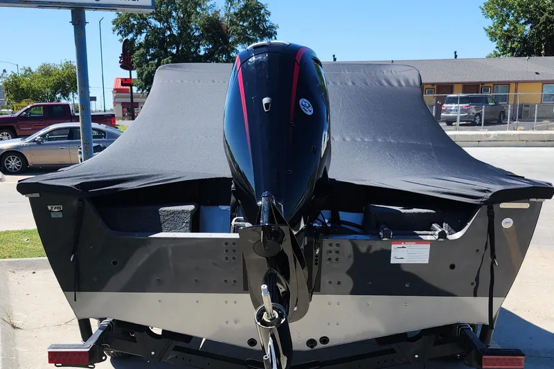 Slide: The Image of 2025 Lund 1775 Impact XS Sport boat with covered motor, parked outdoors. - 22