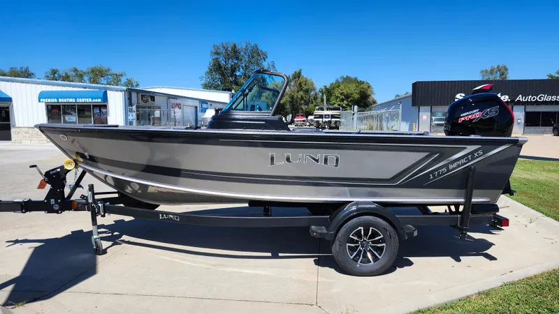 Slide: The Image of 2025 Lund 1775 Impact XS Sport boat on trailer, parked outdoors. - 3
