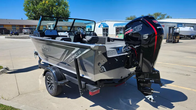 Slide: The Image of 2025 Lund 1775 Impact XS Sport boat with powerful outboard motor in a parking lot. - 6