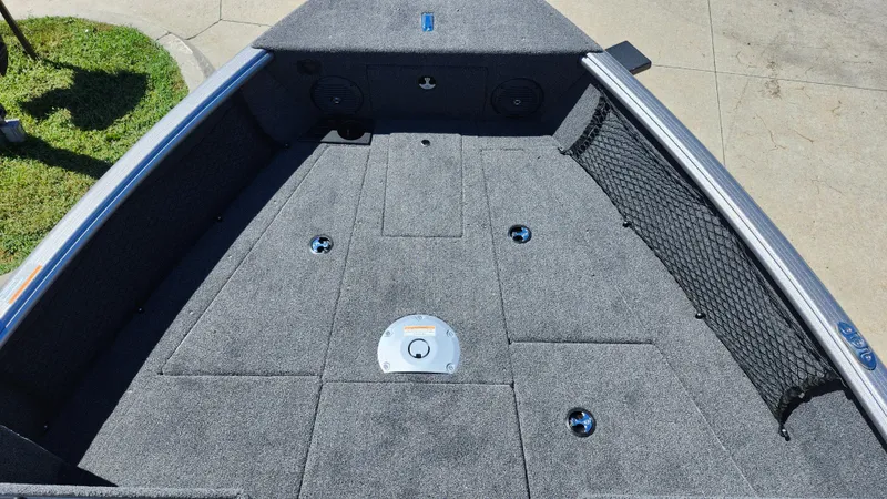 Slide: The Image of 2025 Lund 1775 Impact XS Sport boat deck with carpeted surface and storage compartments. - 9