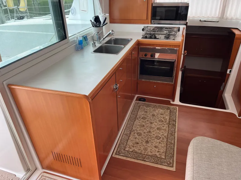 Slide: The Image of Lagoon 420 yacht kitchen interior, 2007 model, featuring wood cabinetry and modern appliances. - 16