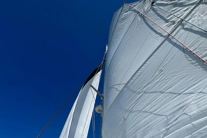 Slide: The Image of Sails of a 2007 Lagoon 420 catamaran against a clear blue sky. - 44