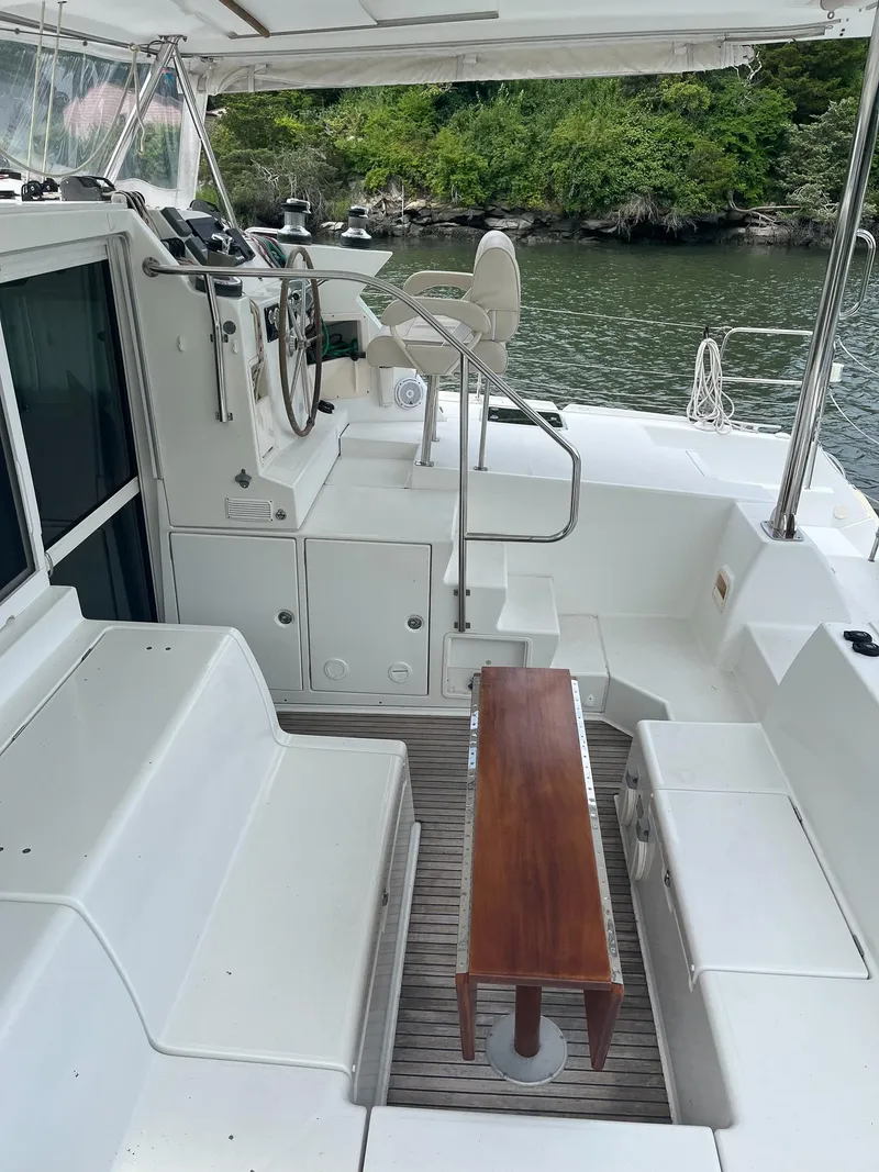 Slide: The Image of 2007 Lagoon 420 yacht deck with seating and steering, near lush shoreline. - 8