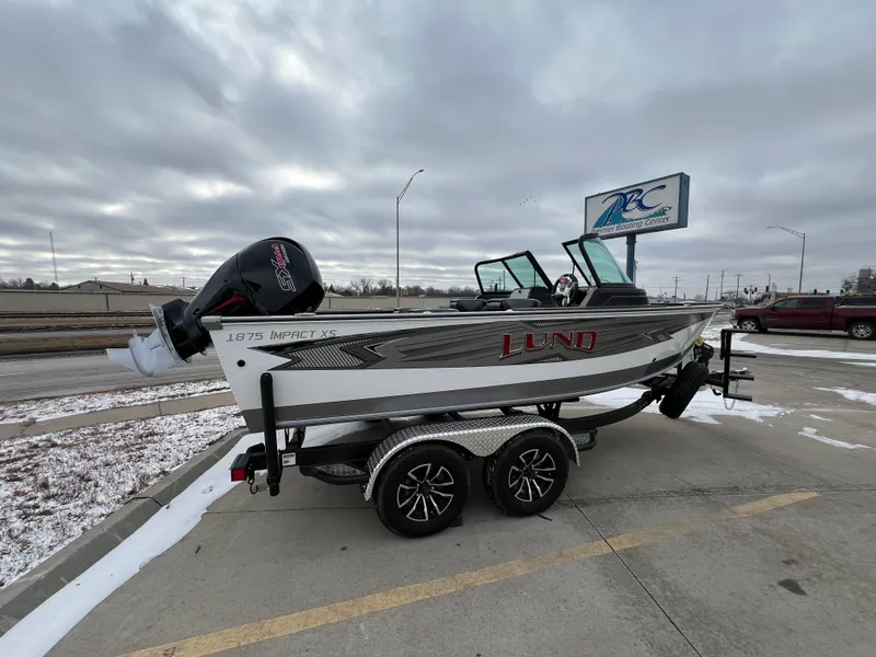 Slide: The Image of 2025 Lund 1875 Impact XS Sport boat on trailer in parking lot. - 1