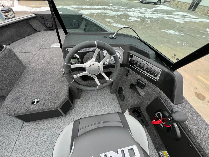 Slide: The Image of 2025 Lund 1875 Impact XS Sport boat interior with steering wheel and control panel. - 21